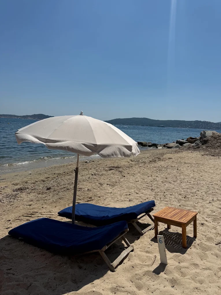 Plage privée Le Pingouin Bleu avec matelas confortables et parasols bleus à Grimaud